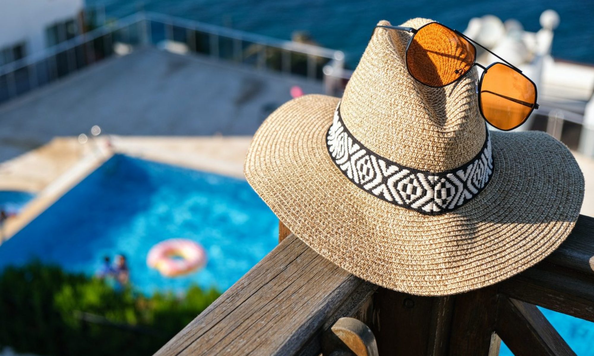 straw-hat-with-sunglasses-wooden-terrace-of-holiday-villa-or-hotel-with-sea-and-wimming-pool-view.jpg